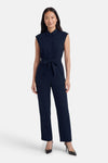 Combinaison bleue de VERO MODA® sans manches, col chemise et taille nouée, portée avec des escarpins noirs.