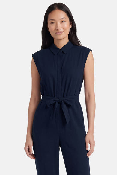 Combinaison bleue de VERO MODA®, sans manches, avec col, boutonnée et ceinture à nouer, portée par une femme.