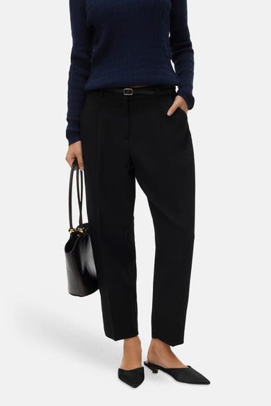 Zwarte broek van VERO MODA met een dunne riem, gedragen met een marineblauwe trui en zwarte muiltjes.