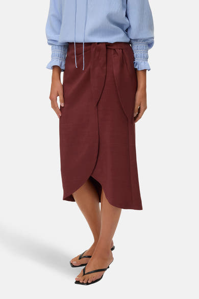 Driekwart rok baksteen van VERO MODA, wikkelstijl, met een blauwe blouse en zwarte sandalen.