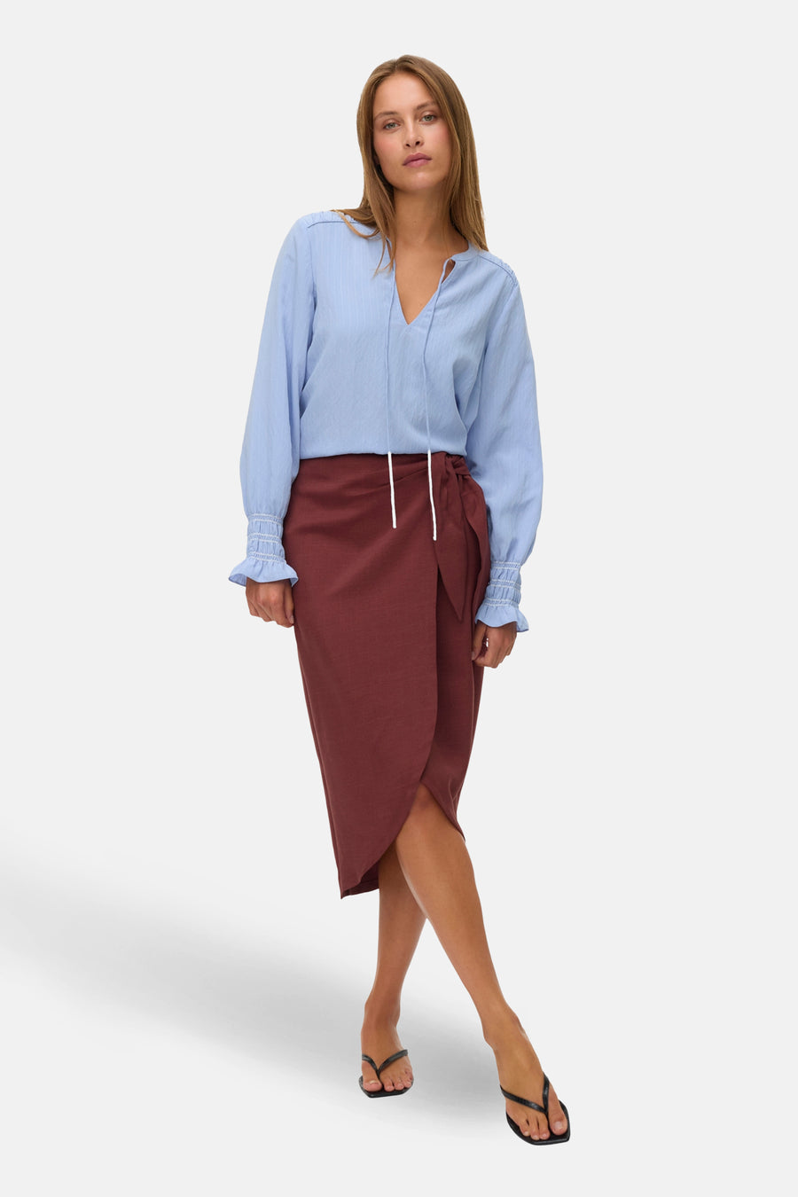 Jupe trois-quarts brique de VERO MODA, style portefeuille, avec une blouse bleue et des sandales noires.