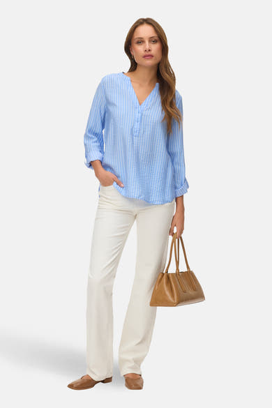 Chemisier bleu à manches longues de VERO MODA®, à rayures verticales, porté avec un pantalon blanc et un sac marron.