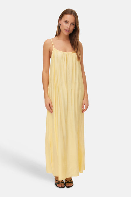 Robe longue jaune de VERO MODA à fines bretelles et texture plissée, portée avec des sandales noires.