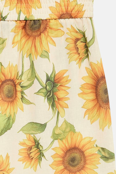 Pantalon coloré jaune de VERO MODA® avec un motif floral tournesol sur un fond écru.