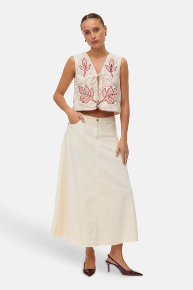 Ecru gilet geborduurd door VERO MODA met roze bladerenmotieven, strikbandjes, gedragen over een lange ecru rok en bordeaux pumps.
