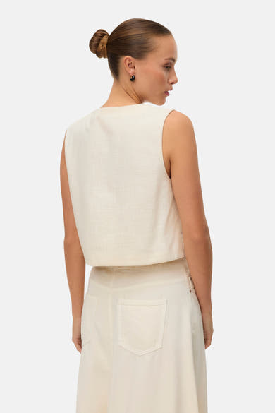 Gilet écru sans manches de VERO MODA®, en tissu texturé, vu de dos, porté avec une jupe assortie.