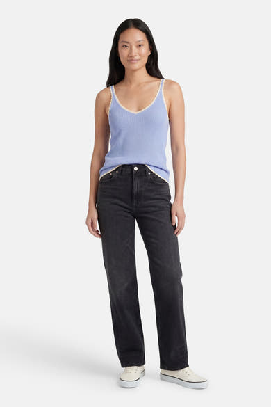 Débardeur bleu côtelé de VERO MODA® avec bordure en dentelle blanche au col et à l'ourlet, porté avec un jean foncé et des baskets.
