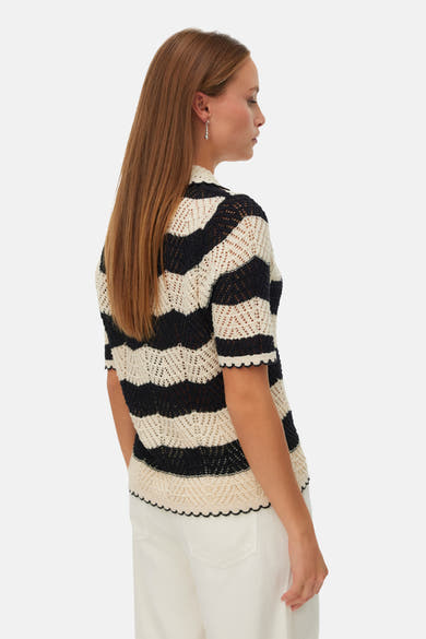 Gilet noir et écru à rayures de VERO MODA en maille ajourée, col montant et ourlet festonné, porté de côté.