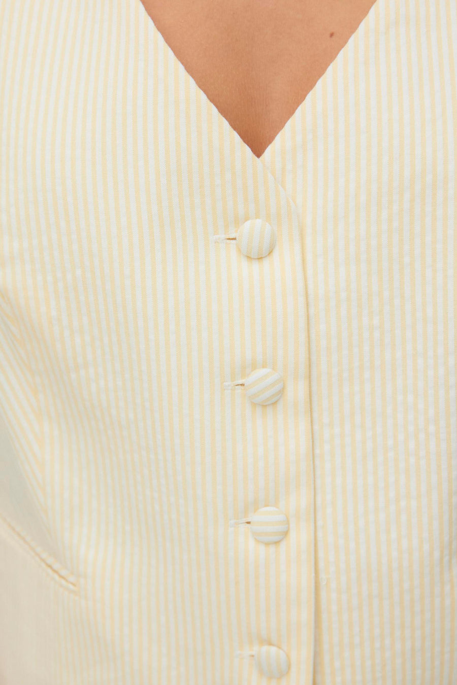 Gilet jaune rayé de VERO MODA®, à fines rayures verticales et boutons décoratifs sur le devant.