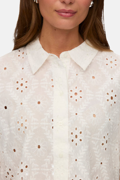 Chemise à manches courtes blanche de VERO MODA® avec broderie anglaise florale, portée par une femme.