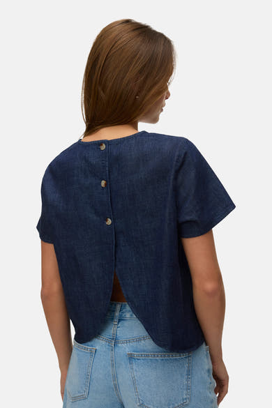 Kortemouwen blouse in donkerblauw denim van VERO MODA, gedragen met een spijkerbroekshort en sandalen met hak.