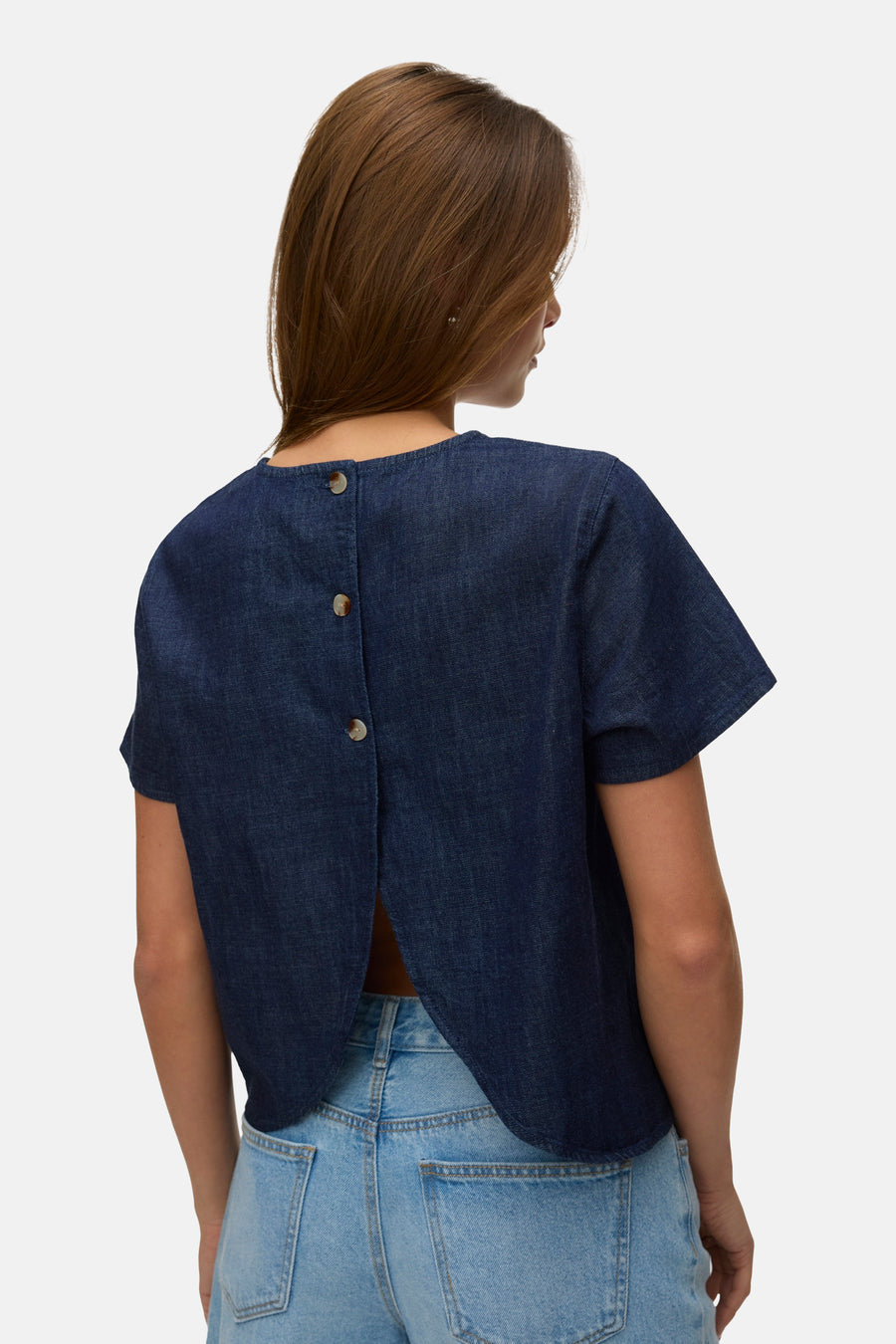 Kortemouwen blouse in donkerblauw denim van VERO MODA, gedragen met een spijkerbroekshort en sandalen met hak.