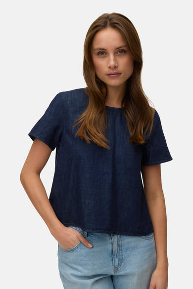 Kortemouwblouse in donkerblauw denim van VERO MODA, met lichtblauwe jeans en lang haar.