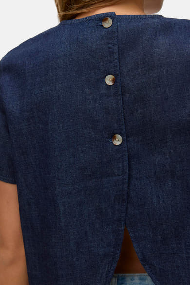 Kortemouwenblouse van donkerblauw denim van VERO MODA, met knoopsluiting aan de achterkant en een losse pasvorm.