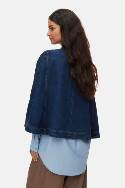 Veste en denim bleu foncé de VERO MODA, avec coupe cape sur une chemise bleu clair et un pantalon marron.
