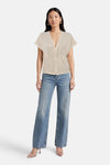 T-shirt beige à manches courtes de Vero Moda, porté avec un jean bleu et des escarpins transparents.
