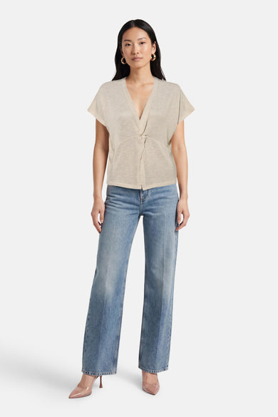 T-shirt beige à manches courtes de Vero Moda, porté avec un jean bleu et des escarpins transparents.
