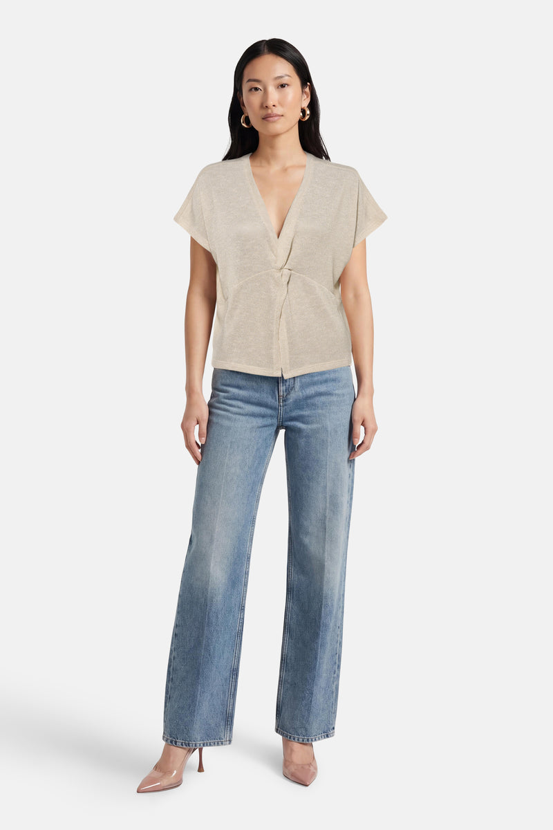 T-shirt beige à manches courtes de Vero Moda, porté avec un jean bleu et des escarpins transparents.
