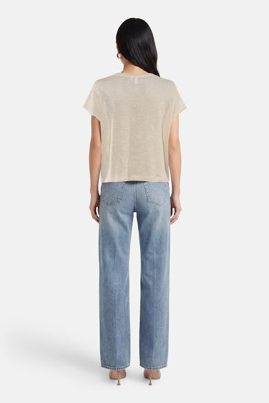 T-shirt beige à manches courtes de VERO MODA, porté avec un jean bleu taille haute et des escarpins.