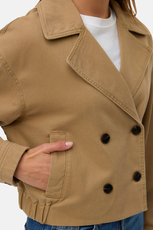 Veste courte marron de VERO MODA, avec double boutonnage et poches avant, portée sur un t-shirt blanc.