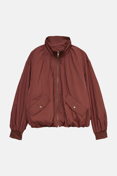 Bruin regenjas van VERO MODA® met klepzakken en ritssluiting, op neutrale achtergrond.