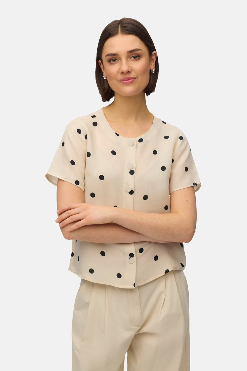 Multikleurig overhemd met korte mouwen van VERO MODA®, met zwart stippenpatroon op een beige achtergrond.