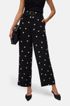 Zwarte broek met witte stippen van Vero Moda, losse en vloeiende pasvorm, gedragen met zwarte muiltjes.