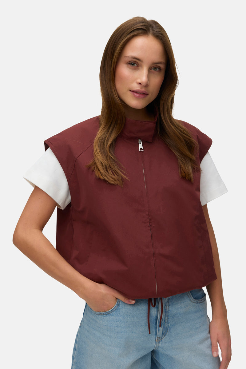 Rood mouwloos vest van VERO MODA, gedragen met een wit T-shirt en een lichtblauwe spijkerbermuda.