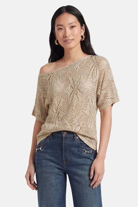 Pull beige en maille ajourée de VERO MODA, à manches courtes et porté sur l'épaule.