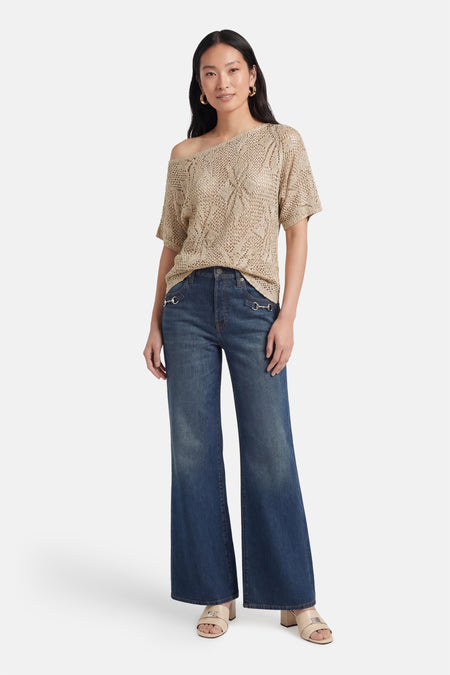 Pull beige en maille ajourée de VERO MODA, col bateau, manches courtes, porté avec un jean et des mules.