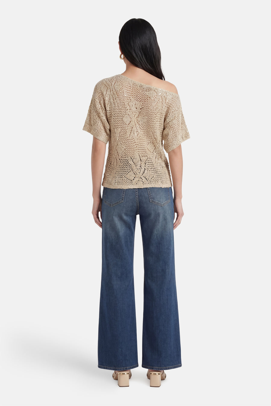 Pull beige de VERO MODA® en maille ajourée, manches courtes, épaule dénudée, vue de dos, avec un jean large.