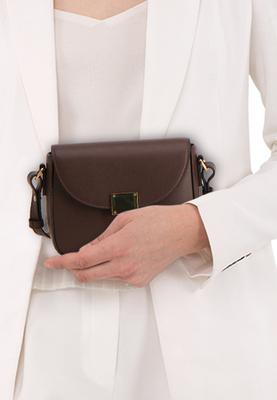 Sac à bandoulière brun de VERO MODA, avec fermoir doré, porté avec un tailleur blanc.
