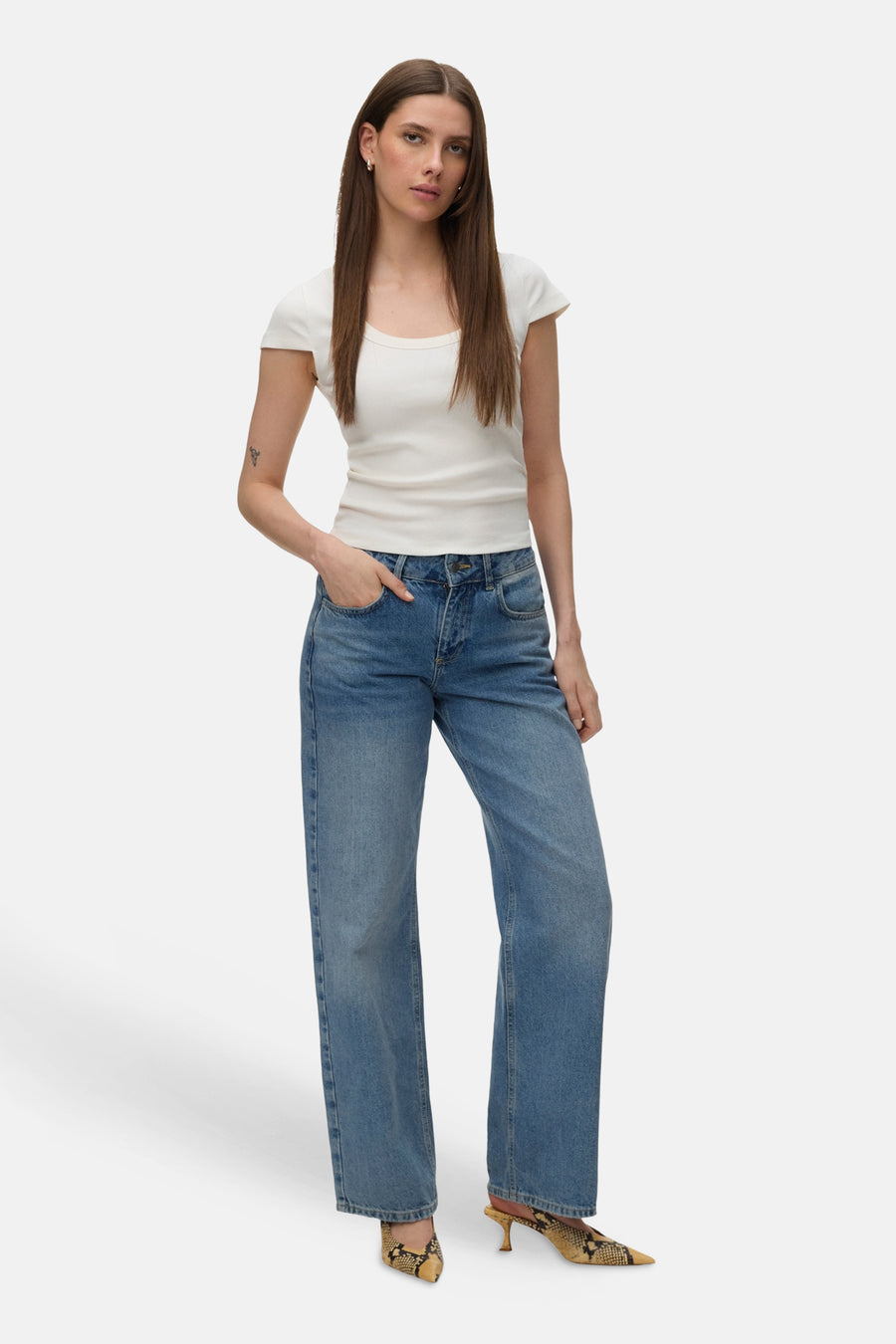 T-shirt blanc uni de VERO MODA® à manches courtes et côtelé, porté avec un jean et des mules à motif serpent.