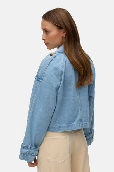 Veste courte en denim bleu clair de VERO MODA, avec boutons aux épaules et poches beiges.