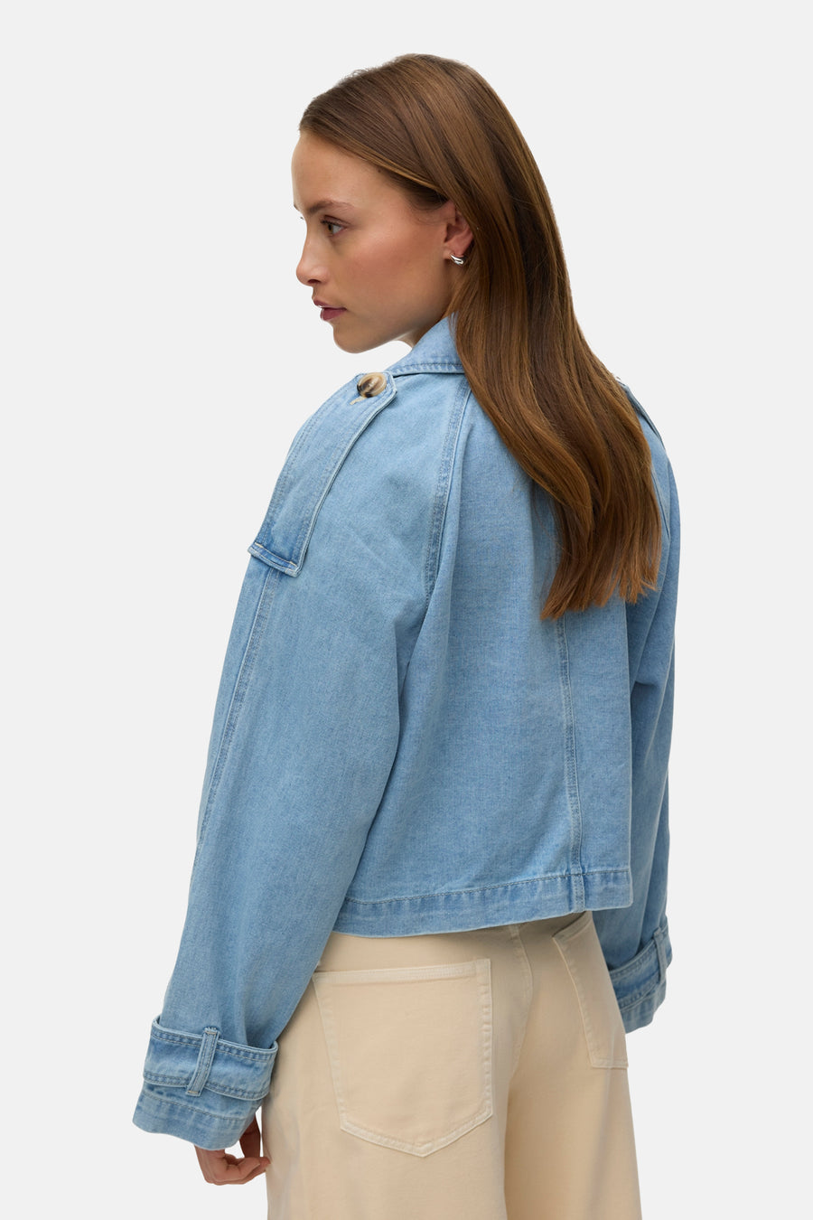 Veste courte en denim bleu clair de VERO MODA, avec boutons aux épaules et poches beiges.