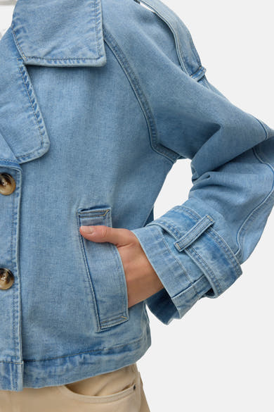 Veste courte en denim bleu clair de VERO MODA, avec des poches et des boutons marron.