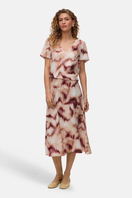 Chemisier multicolore à manches courtes de VERO MODA® avec motif abstrait rose, beige et bordeaux, porté avec une jupe assortie.