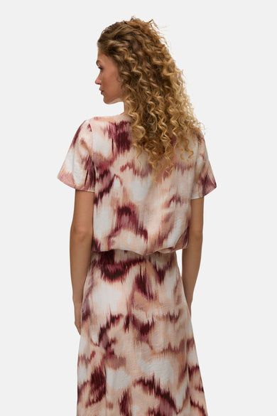 Chemisier multicolore à manches courtes de VERO MODA®, motif abstrait rose et bordeaux, porté par une femme de dos.