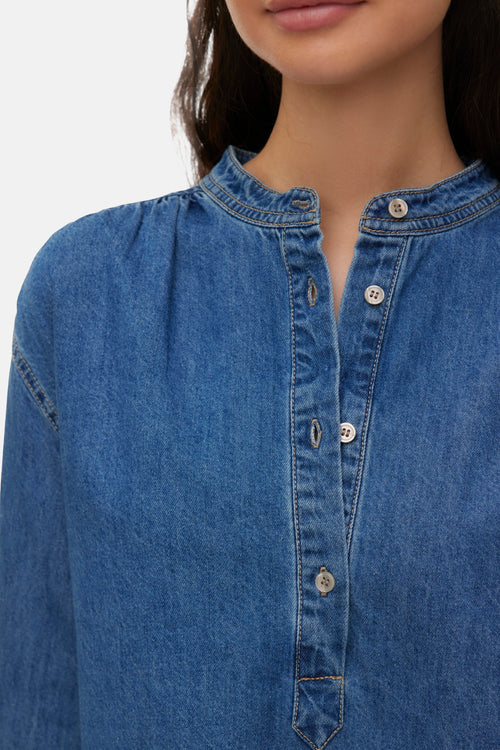 Medium blue denim long-sleeve blouse with button placket and contrast stitching, close-up front view