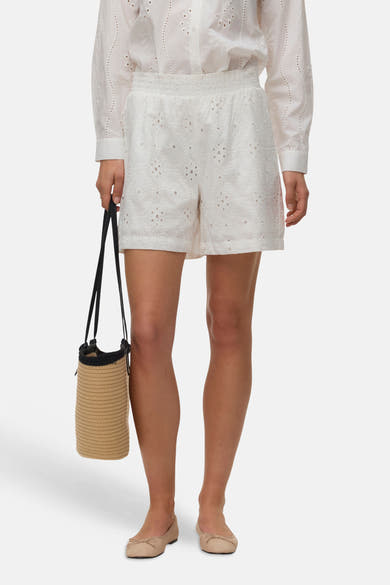 Short blanc de VERO MODA® en broderie anglaise à taille smockée, avec chemise et sac en paille.
