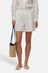 Short blanc de VERO MODA® en broderie anglaise à taille smockée, avec chemise et sac en paille.