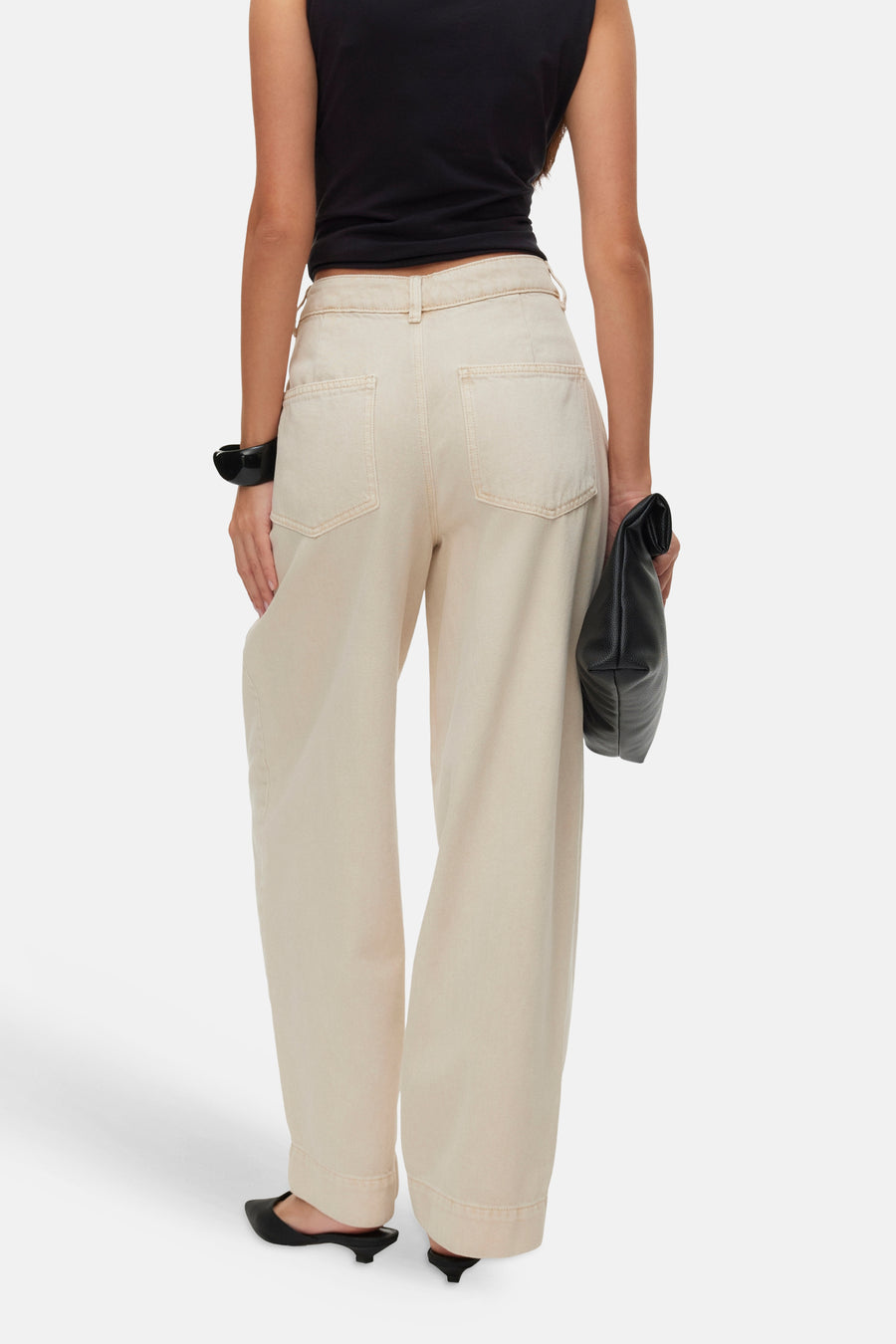 Beige wide-leg jeans by VERO MODA, back view with cuffed hems and two rear pockets, worn with black top and heels