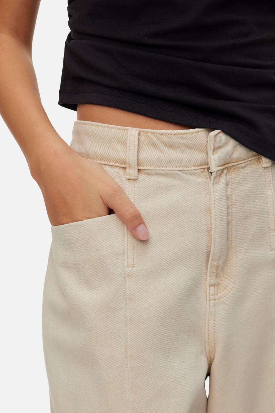 Beige colored jeans by VERO MODA, cropped front view with hand in pocket, worn with black top, textured denim fabric