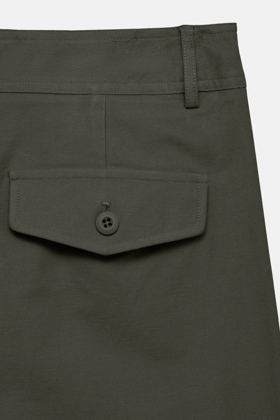 Dark olive colored pants with textured fabric and buttoned flap pocket, close-up side view