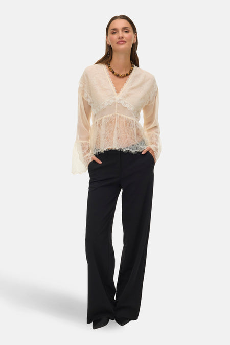 Blouse à manches longues écru de VERO MODA, avec dentelle florale et pantalon noir.