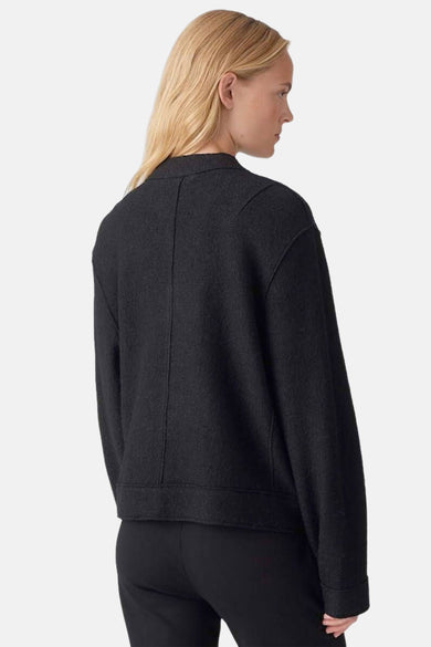 Korte zwarte jas van OPUS, met een licht gemêleerde textuur, van achteren gezien, gedragen met een zwarte broek.