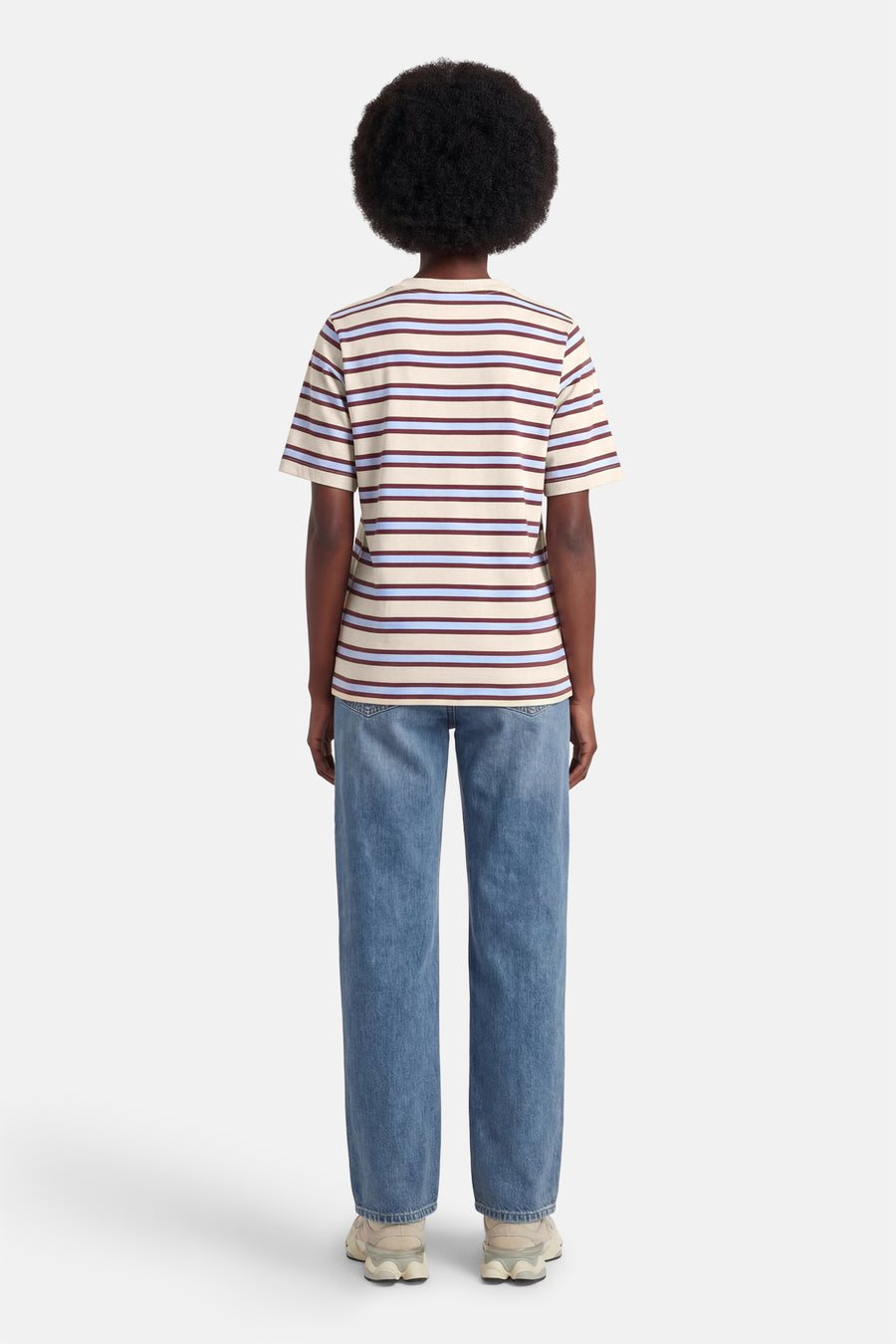 T-shirt à manches courtes multicolore de VERO MODA®, rayures horizontales, porté avec un jean bleu ample et des baskets couleur crème.