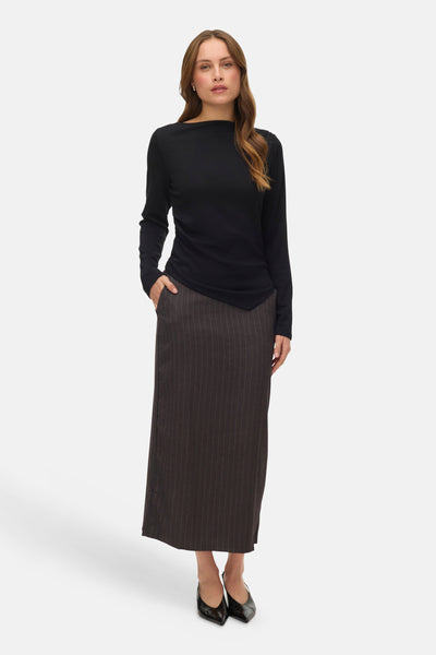 Zwart T-shirt met lange mouwen van VERO MODA, gedragen met een lange rok met fijne strepen en zwarte schoenen.