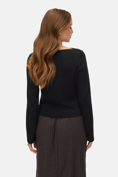 Zwart T-shirt met lange mouwen van VERO MODA, gedragen met een rok met verticale strepen, van achteren gezien.