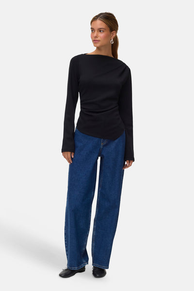 Black long-sleeve t-shirt with boat neckline and slim fit, worn with blue wide-leg jeans and black shoes, full-body front view